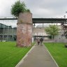 Vers le hall d'accueil de La Piscine.  Dans le Jardin Thérèse Constans, une cheminée en briques, vestige de l'usine textile Hannart Frères